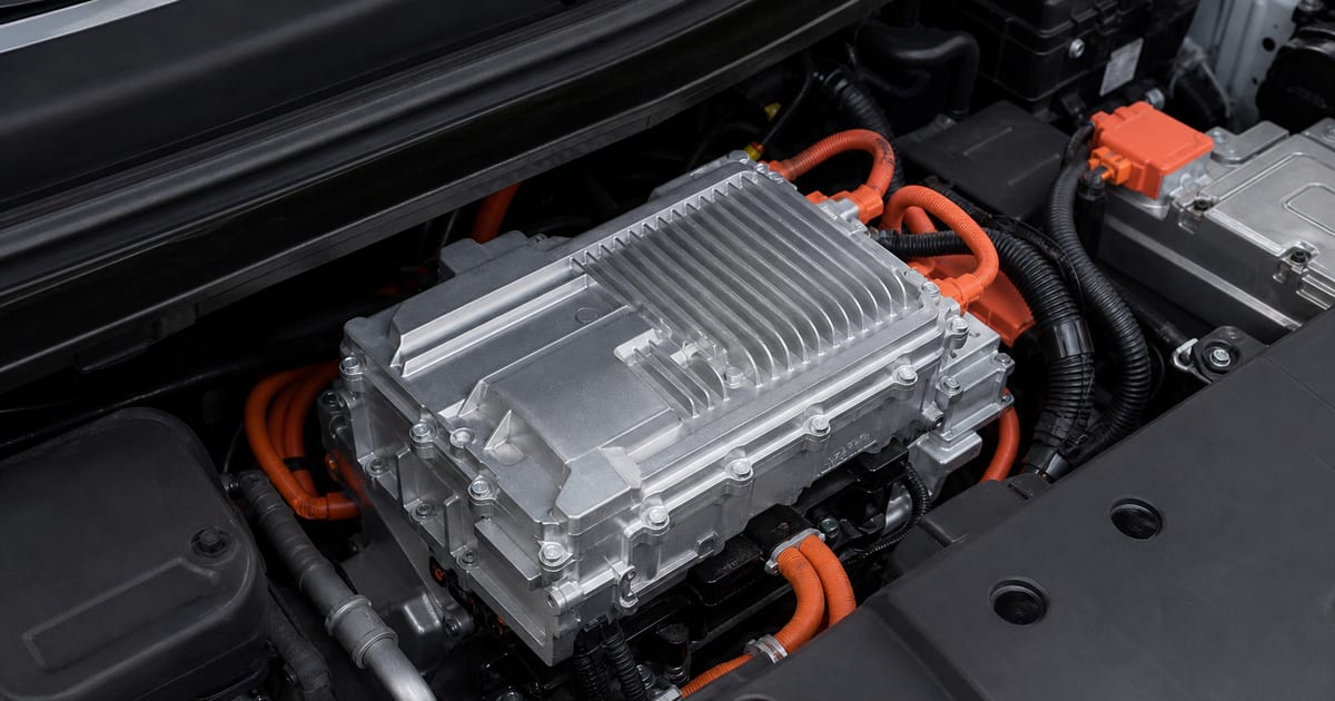 Onduleur automobile en aluminium avec connecteurs orange dans un compartiment technique ouvert