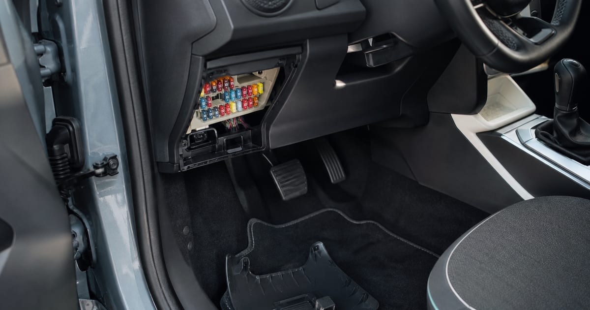 Boîtier de fusibles accessible sous le tableau de bord d’une voiture compacte